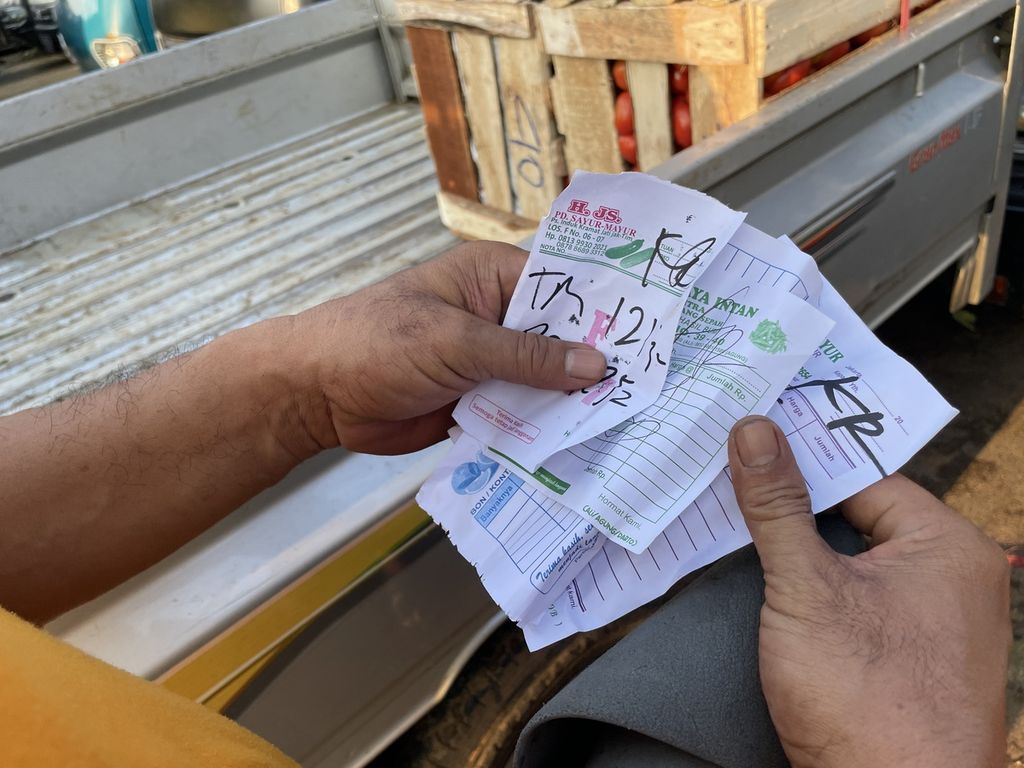 Seorang kuli angkut melihat bon belanjaan pembeli di Pasar Induk Kramat Jati, Pasar Induk Kramat Jati, Jakarta Timur, Rabu (8/3/2023). Bon menjadi panduan bagi kuli angkut untuk mengambil barang belanjaan pembeli dari lapak dan mengangkutnya ke pikap atau kendaraan pembeli.