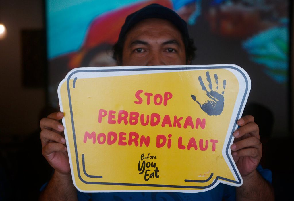 Kasan Kurdi, sutradara film dokumenter <i>Before You Eat</i> yang diprakarasi oleh Greenpeace Indonesia dan Serikat Buruh Migran Indonesia, membawa poster kampanye tentang perbudakan di laut saat acara nonton bersama di Kota Lama, Kota Semarang, Jawa Tengah, Senin (21/3/2022). Film tersebut mengisahkan kekerasan yang dialami anak buah kapal penangkap ikan di luar negeri.