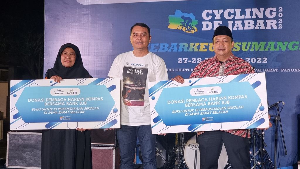 Redaktur Pelaksana Harian <i>Kompas </i>Adi Prinantyo bersama dua perwakilan sekolah penerima buku bantuan dari Dana Kemanusiaan Kompas dan Bank BJB dalam Ajang Cycling De Jabar 2022 di Pantai Rancabuaya, Kecamatan Caringin, Kabupaten Garut, Jawa Barat, Sabtu (27/8/2022).