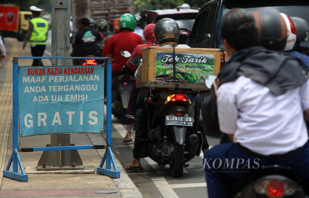 Papan pemberitahuan uji emisi gratis dipasang di pinggir jalan menuju lokasi pengujian di halaman GOR Senam DKI Raden Inten, Jakarta Timur, Selasa (29/3/2022). Uji emisi kendaraan bermotor merupakan salah satu cara menekan laju pencemaran udara dari kendaraan bermotor.