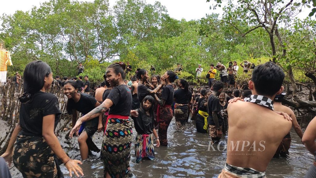 <i>Krama</i> (warga) dan <i>yowana </i>(pemuda dan pemudi) Desa Adat Kedonganan, Kedonganan, Kuta, Kabupaten Badung, saling membalurkan lumpur hutan bakau ketika mengikuti tradisi <i>mabuug-buugan </i>di tengah hutan mangrove Taman Hutan Raya Ngurah Rai, Kamis (23/3/2023).