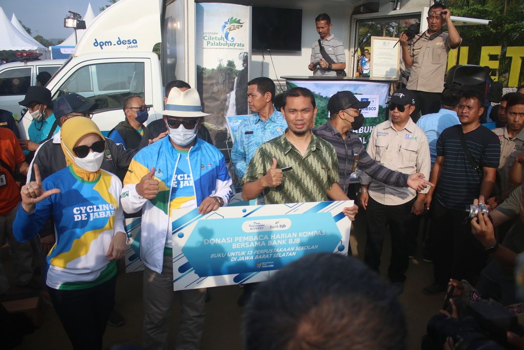 Gubernur Jawa Barat Ridwan Kamil (topi pedora putih) bersama perwakilan sekolah penerima buku bantuan dari Dana Kemanusiaan <i>Kompas </i>dan Bank BJB dalam Ajang Cycling De Jabar 2022 di Pantai Geopark Ciletuh, Kecamatan Ciemas, Kabupaten Sukabumi, Jabar, Sabtu (27/8/2022).