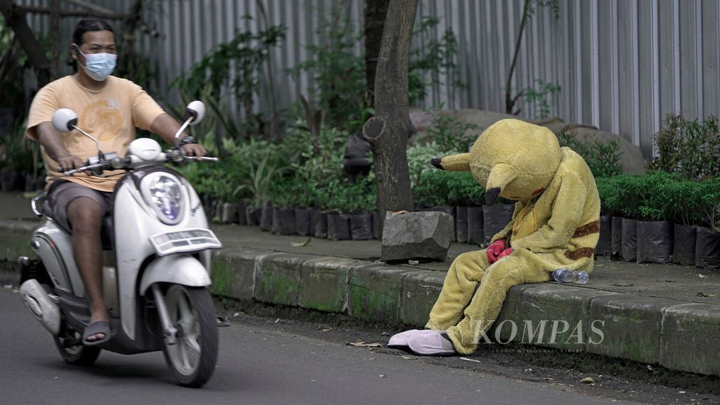 Badut jalanan meminta belas kasihan pengguna jalan di Taman Hutan Tebet, Jakarta Selatan, Sabtu (13/2/2021). 