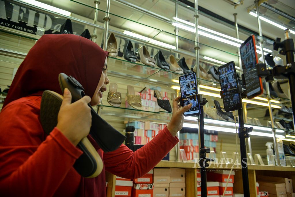 Pedagang berinteraksi dengan penonton di media sosial Tiktok saat menawarkan dagangannya secara langsung lewat daring di kios Blok A Tanah Abang, Jakarta, Selasa (13/6/2023). Penjualan secara daring menjadi salah satu strategi pedagang untuk menjangkau konsumen yang lebih luas.