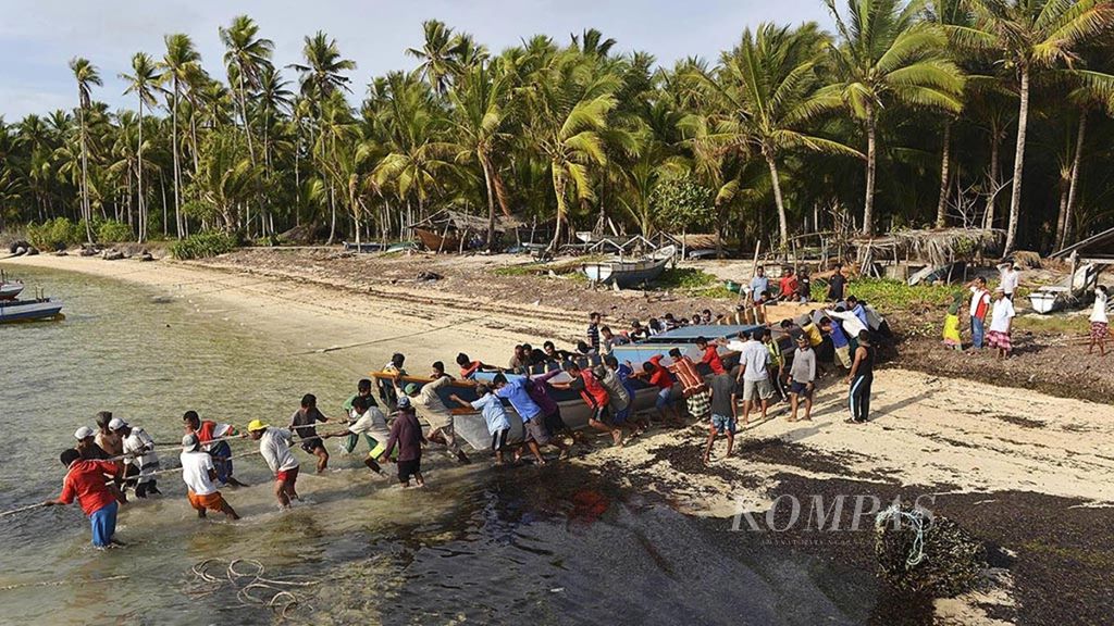 Warga bergotong-royong mendorong perahu milik salah satu warga yang telah selesai dibuat di Desa Jaya Makmur, Kecamatan Binongko, Wakatobi, Sulawesi Tenggara, Rabu (27/9). Tradisi gotong royong membantu sesama masih kental dipegang dan dilestarikan masyarakat di daerah ini. Kompas/Heru Sri Kumoro (KUM) 27-09-2017