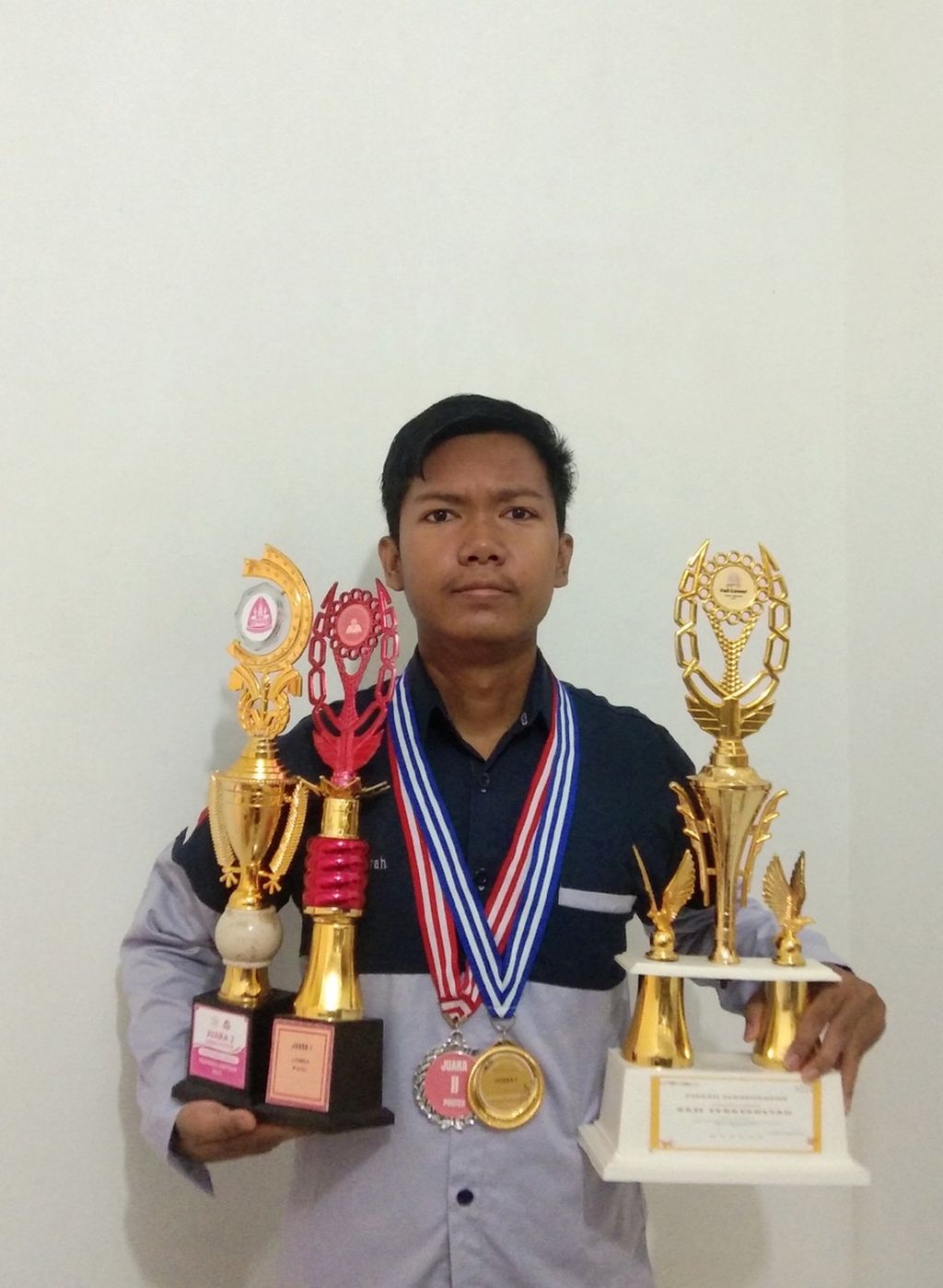 Arif Febriansyah dan piala-piala yang diraihnya dari lomba desain poster.