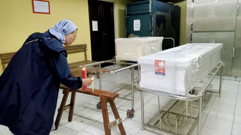 Sr Laurentia PI menyalakan lilin di bawah kaki peti jenazah Oce Liu (31) yang dibunuh suaminya di Malaysia, saat jenazah itu disemayamkan di RSUD WZ Yohannes Kupang, Jumat (17/2/2023). Oce Liu dibunuh suami karena cemburu. Dalam lima tahun terakhir, Sr Laurentia PI telah menangani 657 peti jenazah yang dikirim melalui Bandara El Tari Kupang.