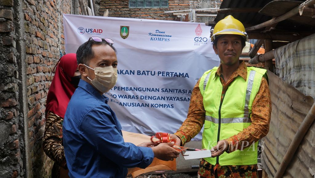 Direktur Yayasan Dana Kemanusiaan Kompas Antonius Tomy Trinugroho (kiri) melakukan peletakan batu pertama untuk pembangunan sanitasi aman di rumah milik penerima manfaat, di Kelurahan Mojo, Kecamatan Pasar Kliwon, Kota Surakarta, Jawa Tengah, Rabu (26/10/2022). Bantuan sanitasi aman bersumber dari dana donasi pembaca <i>Kompas </i>yang dikelola oleh Yayasan Dana Kemanusiaan Kompas.