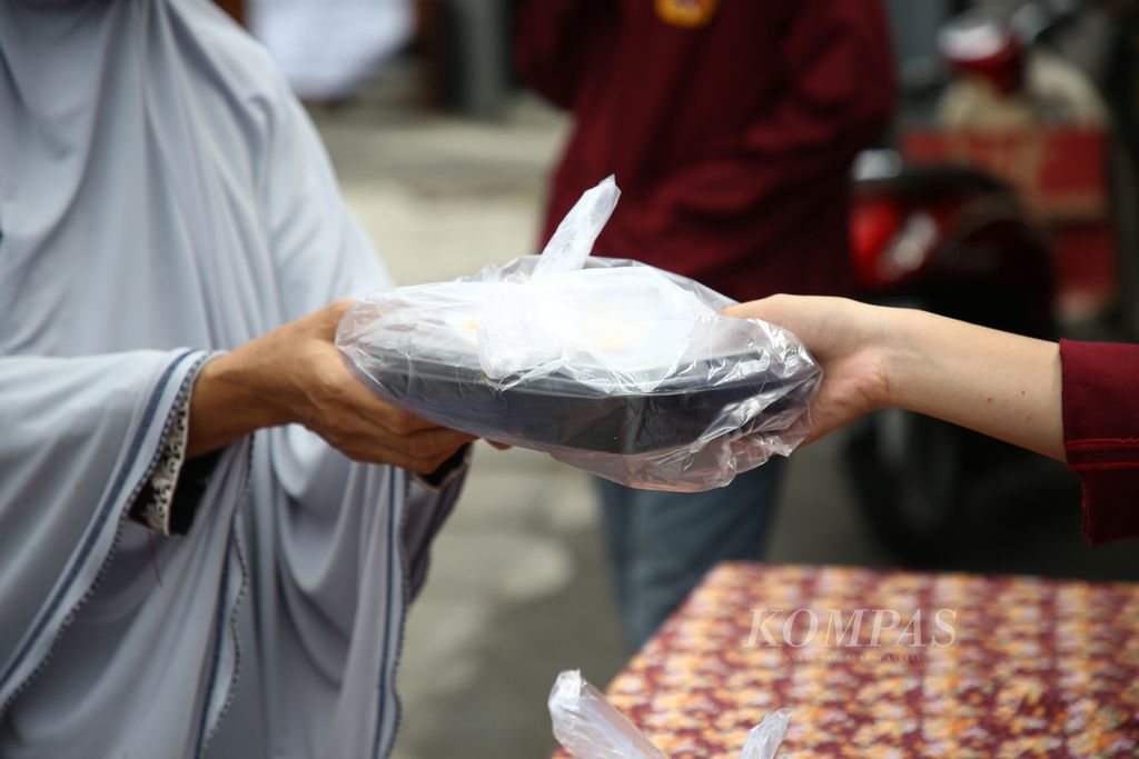 Warga membeli nasi yang dijual dengan membayar seikhlasnya oleh siswa SMA Kebangsaan di depan sekolah mereka di jalan raya Pondok Aren, Tangerang Selatan, Banten, Jumat (18/12/2020). Kegiatan berbagi nasi pada masa pandemi ini dilakukan dengan modal awal uang iuran yang mereka kumpulkan. Dana yang terkumpul digunakan untuk kegiatan serupa di lain waktu. 