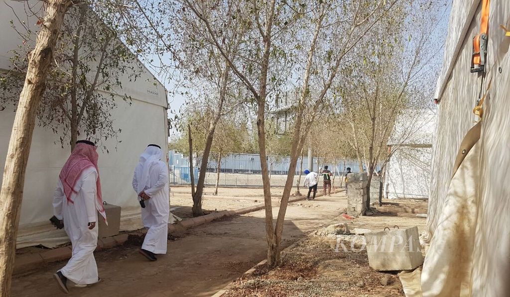 Dua pengurus maktab berjalan di tengah kawasan perkemahan untuk jemaah haji di Arafah, Mekkah, Arab Saudi, Kamis (30/6/2022). Perkemahan haji di kawasan ini dikebut untuk menyambut jemaah haji yang akan melakukan wukuf pada Jumat (8/7/2022). 