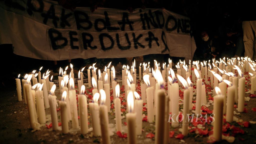 Lilin dinyalakan pencinta sepak bola yang berkumpul di pintu masuk Asia Afrika, Stadion Gelora Bung Karno, Jakarta, Minggu (2/10/2022) malam. Mereka mengadakan aksi tabur bunga, menyalakan 1.000 lilin dan doa bersama untuk menghormati kawan-kawan Aremania yang menjadi korban tragedi Kanjuruhan seusai laga Arema FC melawan Persebaya. Tragedi Kanjuruhan mengakibatkan 125 orang meninggal dan 180 orang menjalani perawatan. 