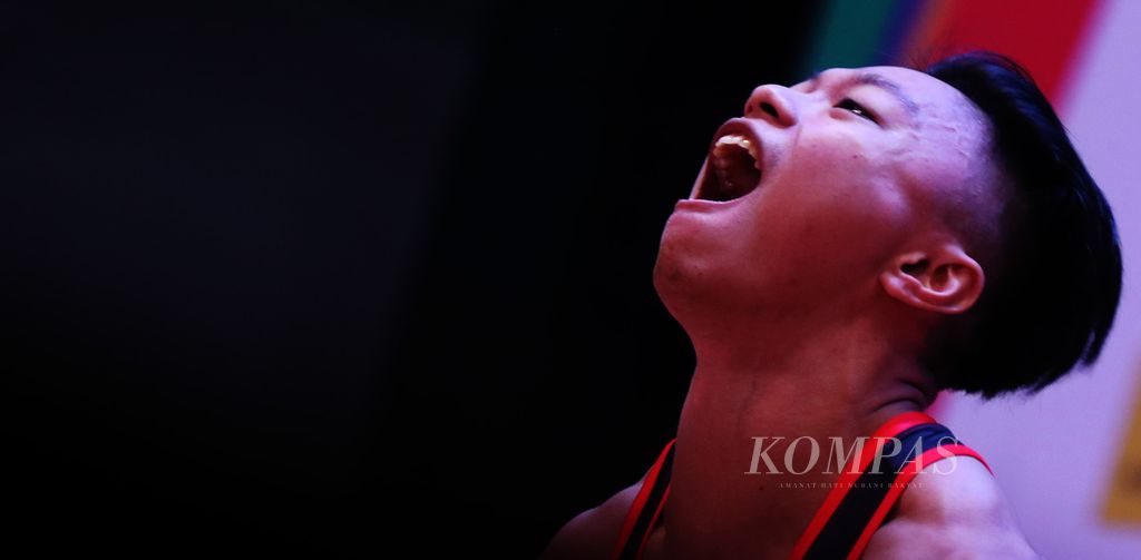 Ekspresi lifter Indonesia, Rahmat Erwin Abdullah, saat beraksi melakukan angkatan dalam nomor 73 kilogram putra cabang angkat besi pada SEA Games Vietnam 2021 di Hanoi Training Center, Hanoi, Vietnam, Sabtu (21/5/2021) . 