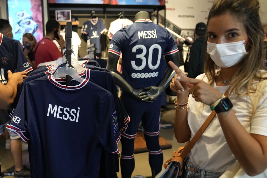Suporter PSG melihat jersei Lionel Messi di outlet resmi PSG di Paris, Perancis (11/8/2021). Kepindahan Messi ke PSG membuat jersei diburu suporter PSG.