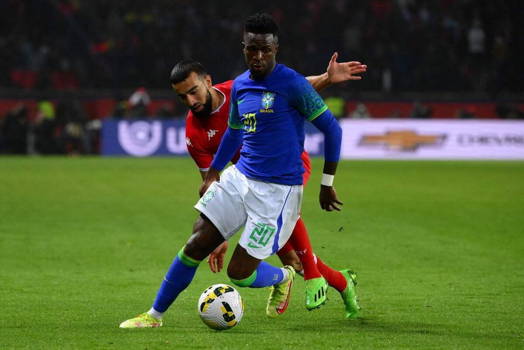 Pemain timnas Brasil Vinicius Junior (kanan) berebut bola dengan kiper Tunisia Bechir Ben Saïd laga persahabatan di Stadion Parc des Princes, Paris, (Selasa (27/9/2022). Brasil menang dengan skor 5-1. 