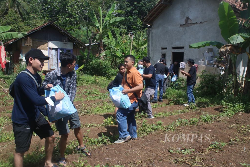 Sejumlah karyawan Kompas Gramedia dan sukarelawan menyalurkan bantuan di Kampung Sedong Kulon, Kelurahan Bojongherang, Kecamatan Cianjur, Kabupaten Cianjur, Jawa Barat, Sabtu (21/1/2023).