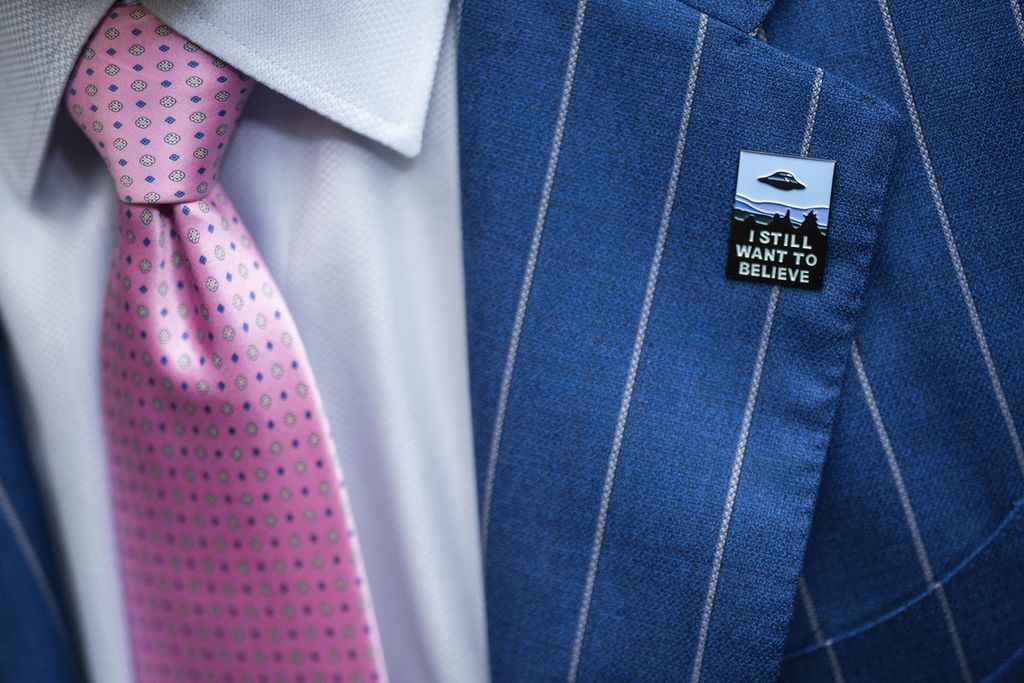 Seorang peserta rapat dengar pendapat Kongres Amerika Serikat memakai pin bertuliskan ”I Want to Believe” (Aku Ingin Percaya) pada 26 Juli 2023. Kongres menyelidiki laporan sejumlah personel militer AS yang mengaku pernah bersirobok dengan makhluk antariksa.