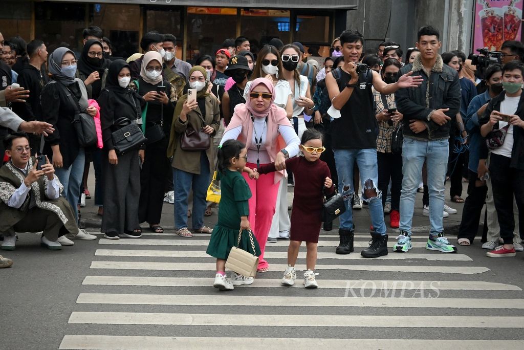 Dua anak kecil bersiap memamerkan aksi <i>fashion show</i> di daerah Dukuh Atas, Kecamatan Tanah Abang, Jakarta Pusat, Senin (25/7/2022) sore. Kawasan yang populer dengan sebutan Citayam Fashion Week ini terbentuk oleh remaja pinggiran yang <i>nongkrong</i>, berbusana kece, dan membuat konten aktualisasi diri.