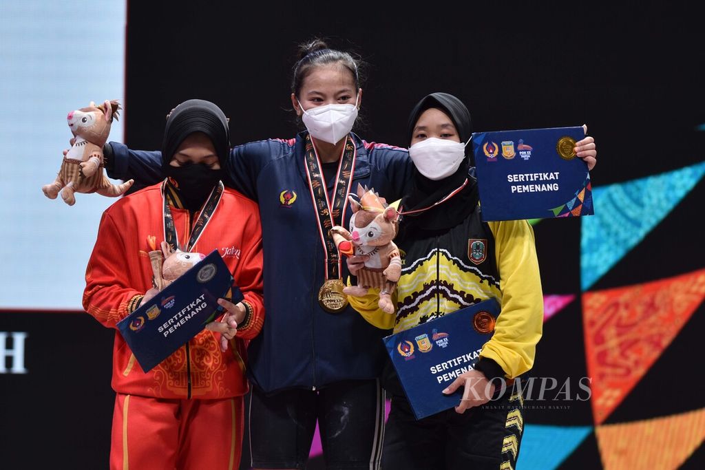 Lifter putri Jabar, Windy Cantika Aisah, naik podium bersama lifter putri Jawa Tengah, Siti Nafisatul (kiri), dan lifter Kalimantan Selatan, Riska Nur Amanda, seusai menyelesaikan angkatan di kelas 49 kg angkat besi PON Papua 2021 di Auditorium Universitas Cenderawasih, Kota Jayapura, Rabu (6/10/2021). 