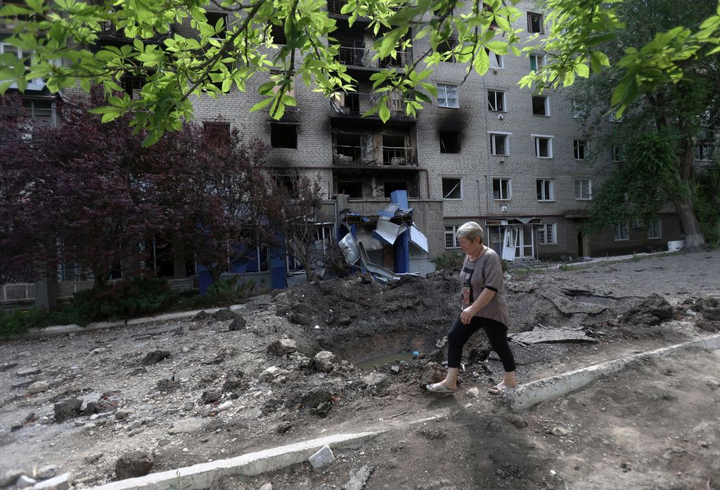 Seorang warga melewati bangunan apartemen warga yang rusak di salah satu sudut kota Lysychansk, Ukraina, Minggu (3/7/2022). Kini, kota itu telah sepenuhnya jatuh ke tangan militer Rusia dan memaksa militer Ukraina mundur. 