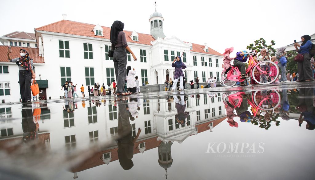 Refleksi wisatawan dengan latar belakang gedung Museum Sejarah Jakarta di taman Fatahilah, Kota Tua, Jakarta, seusai hujan, Sabtu (6/7/2024). Mengutip data Badan Pusat Statistik, jumlah perjalanan wisatawan nasional pada Mei 2024 mencapai 626.670 perjalanan. Jumlah tersebut turun jika dibandingkan dengan April 2024, tetapi naik 5,63 persen secara tahunan.