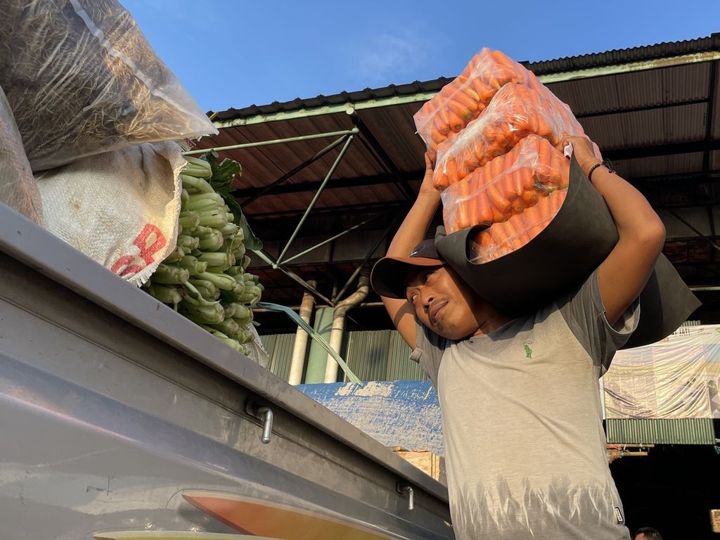 Mistori (43), kuli angkut di Pasar Induk Kramatjati, memikul wortel dari lapak sayuran menuju pikap pembeli di tempat parkir, Rabu (8/3/2023). Kesejahteraan kuli angkut menjadi salah satu tema liputan 4K Suara Tak Terdengar.