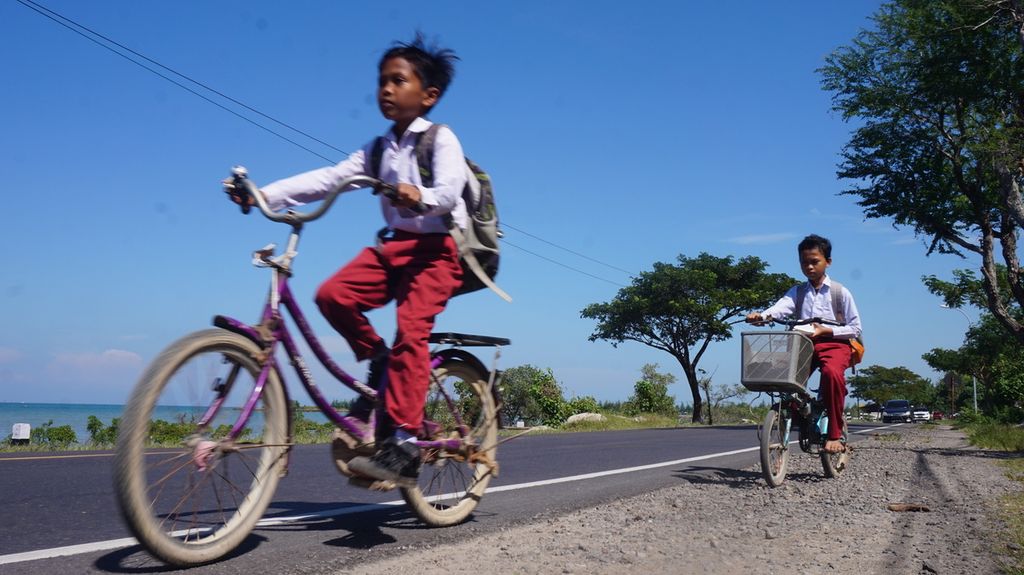 Anak-anak nelayan bersepeda sepulang sekolah di Jalan Raya Pamekasan-Sumenep, Pulau Madura, Jawa Timur, Senin (20/6/2022). Pemerataan pembangunan prasarana dan sarana transportasi serta utilitas termasuk telekomunikasi mendorong peningkatan kualitas sumber daya manusia pesisir. Anak-anak nelayan dapat menikmati pendidikan berkualitas setara dengan masyarakat perkotaan.