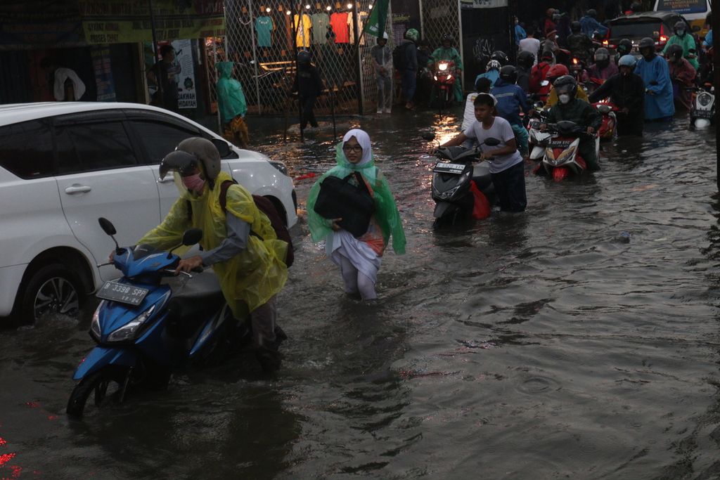 Warga menuntun motor di tengah banjir di Jalan H. Naba Raya, Karang Tengah, Tangerang, Kamis (13/10/2022). Hujan deras disertai petir melanda wilayah Tangerang dan sekitarnya. Sebelumnya, BMKG telah memberi peringatan tentang kemungkinan terjadinya cuaca ekstrem pada 9 hingga 15 Oktober 2022. 