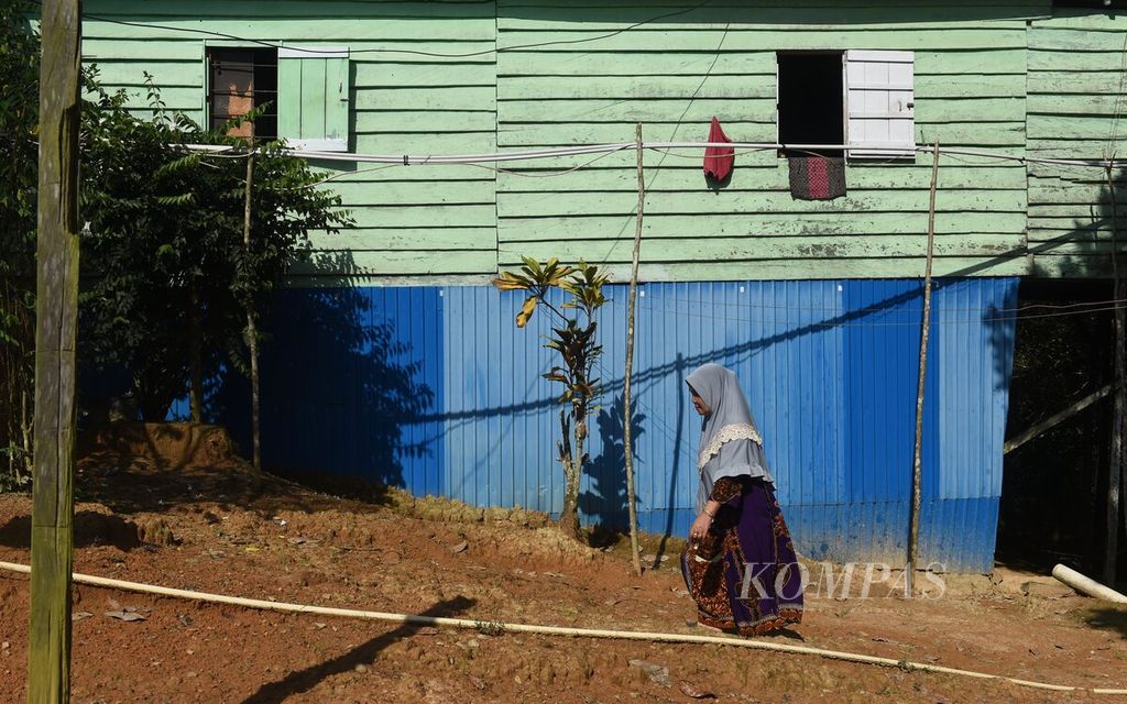 Rania (57) berada di samping rumahnya di Desa Bumi Harapan, Kecamatan Sepaku, Kabupaten Penajam Paser Utara, Kalimantan Timur, Selasa (26/7/2022). Rania mengkhawatirkan pembangunan IKN Nusantara yang saat ini dilakukan memaksanya pindah dari tempat tinggalnya. Ia berharap pembangunan dilakukan tanpa memindahkan pemukiman warga setempat. 
