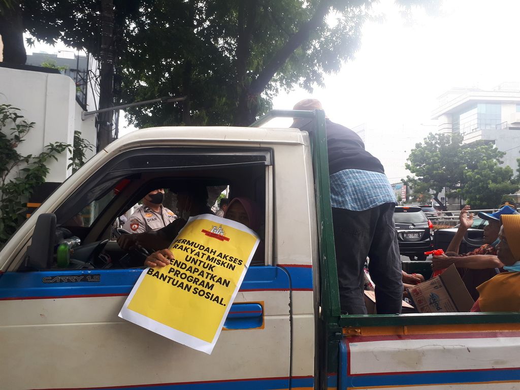 Warga menaiki kendaraan bak terbuka di Kementerian Sosial, Salemba Raya, Jakarta Pusat, Rabu (14/12/2022).