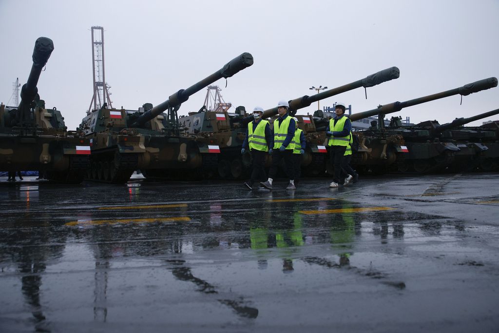 Delegasi Korea Selatan berjalan di depan deretan howitzer K9 Thunder yang diparkir di Pangkalan Angkatan Laut Polandia di Gdynia pada Selasa (6/12/2022).