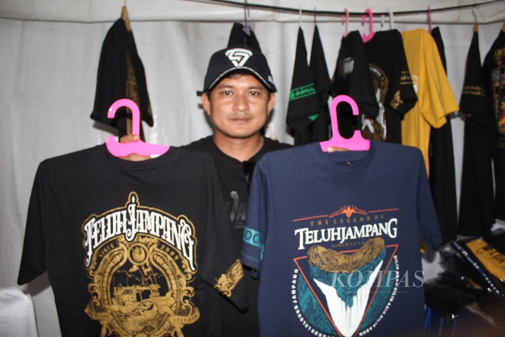 Feri Irawan menunjukkan kaus bermerek Teluh Jampang dalam pameran usaha mikro kecil menengah dalam rangkaian acara Cycling de Jabar di Palangpang, Ciletuh, Kabupaten Sukabumi, Jawa Barat, Kamis (7/7/2023). Ajang balap sepeda itu merupakan wadah promosi bagi UMKM setempat.