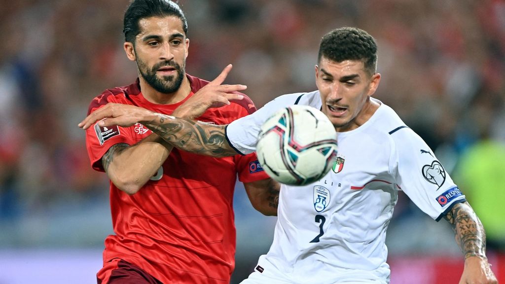 Bek Italia Giovanni Di Lorenzo (kanan) berusaha mengamankan bola dari rebutan pemain belakang Swiss Ricardo Rodriguez. Walau bertandang ke kandang lawan, Italia berhasil unggul tipis dalam mendominasi jalannya pertandingan dengan penguasaan bola sebesar 52 persen. 