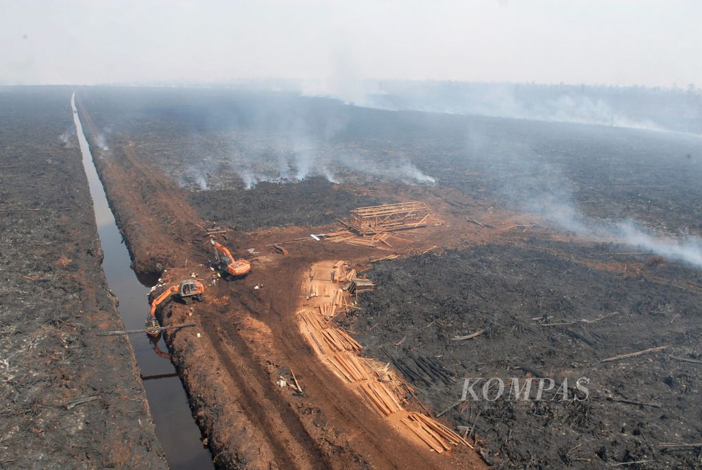 Kayu-kayu yang diambil dari kawasan hutan negara menumpuk dan sebagian lagi dilansir lewat kanal sebuah perusahaan pemegang konsesi hak pengusahaan hutan (HPH), di wilayah Kumpeh, di Kabupaten Muaro Jambi, Selasa (8/10/2019). Patroli udara oleh tim Satuan Tugas Karhutla Jambi mendapati pembalakan masih terus berlangsung di tengah kebakaran yang meluas dalam wilayah hutan itu.
