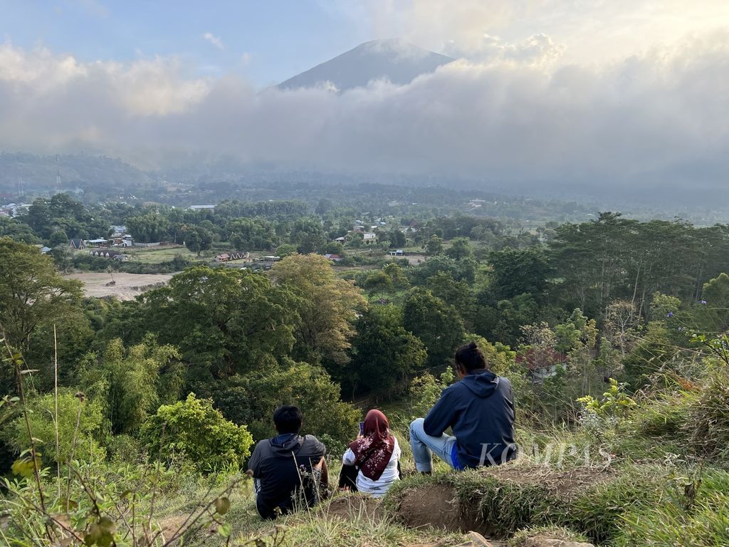 Sejumlah wisatawan menikmati suasana saat Gunung Rinjani tertutup kabut dari Bukit Pegasingan di Desa Sembalun, Kabupaten Lombok Timur, NTB (4/9/2022). Lokasinya yang berada di kaki Gunung Rinjani, membuat Desa Sembalun yang sejak 2016 menjadi desa wisata, 
