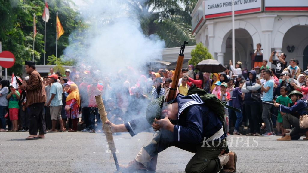 Seorang peserta Parade Surabaya Juang menyalakan meriam saat teatrikal Perang Surabaya 1945 di Monumen Perjuangan Polri, di Surabaya, Minggu (11/11/2018)