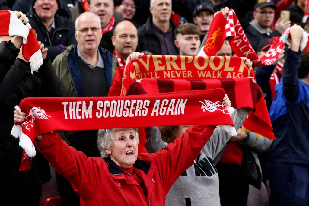 Suporter Liverpool membentangkan syal saat pertandingan Liga Inggris antara Liverpool dan Brighton and Hove Albion di Stadion Anfield, Liverpool, Inggris, Sabtu (2/11/2024). *Liverpool fans hold scarves during the English Premier League football match between Liverpool and Brighton and Hove Albion at Anfield in Liverpool, north west England on November 2, 2024. (Photo by Darren Staples / AFP) / RESTRICTED TO EDITORIAL USE. No use with unauthorized audio, video, data, fixture lists, club/league logos or 'live' services. Online in-match use limited to 120 images. An additional 40 images may be used in extra time. No video emulation. Social media in-match use limited to 120 images. An additional 40 images may be used in extra time. No use in betting publications, games or single club/league/player publications. /