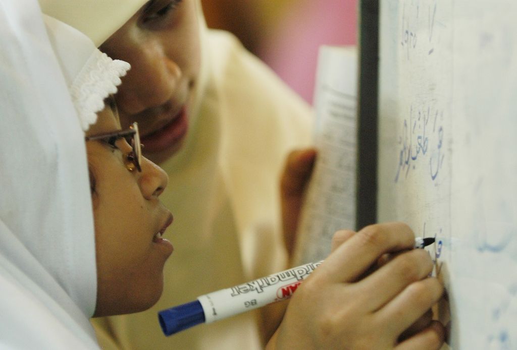 Seorang bocah perempuan dengan dibimbing guru mengaji sedang belajar menulis huruf Arab dalam kegiatan pesantren kilat untuk anak sekolah di Masjid Agung Sunda Kelapa, Jakarta Pusat, Selasa (4/11/2003). Kegiatan pesantren kilat merupakan salah satu kegiatan yang dilakukan remaja masjid untuk mengisi bulan Ramadhan.
