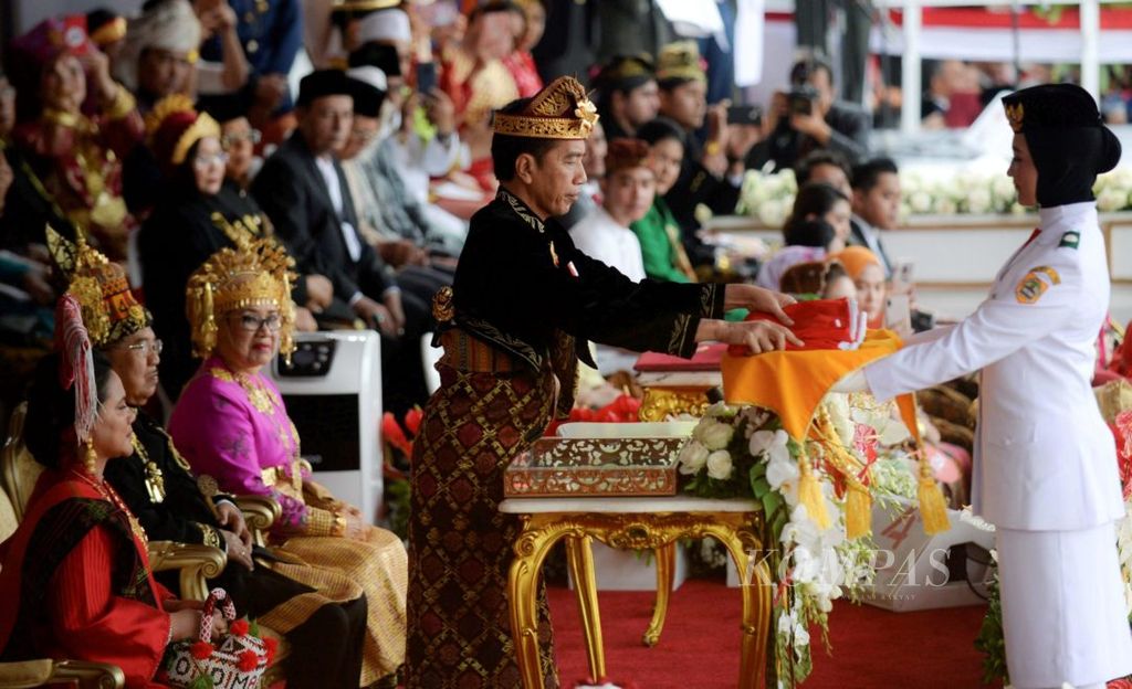 Presiden Joko Widodo menyerahkan Bendera Merah Putih kepada anggota Pasukan Pengibar Bendera Pusaka (Paskibraka) Salma El Mutafaqqiha Putri Achzaabi dalam upacara peringatan HUT ke-74 Republik Indonesia di Istana Merdeka Jakarta, Sabtu (17/8/2019). Kegiatan tersebut diikuti para tamu undangan dengan menggunakan pakaian tradisional dan disemarakkan oleh pentas seni budaya dari berbagai daerah.