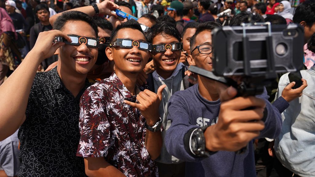 Sejumlah remaja berswafoto sambil menggunakan kacamata gerhana disela-sela mengamati gerahana matahari cincin yang teramati di Lapangan Bunsur, Sungai Apit, Kabupaten Siak, Riau, Kamis (26/12/2019). Fenomena gerhana matahari cincin ini disambut antusias masyarakat setempat dan juga berbagai pendatang dari berbagai kota di Indonesia. Sepanjang tahun 2019, gerhana ini merupakan gerhana kedua yang bisa diamati di wilayah Indonesia setelah gerhana bulan sebagian 17 Juli 2019.