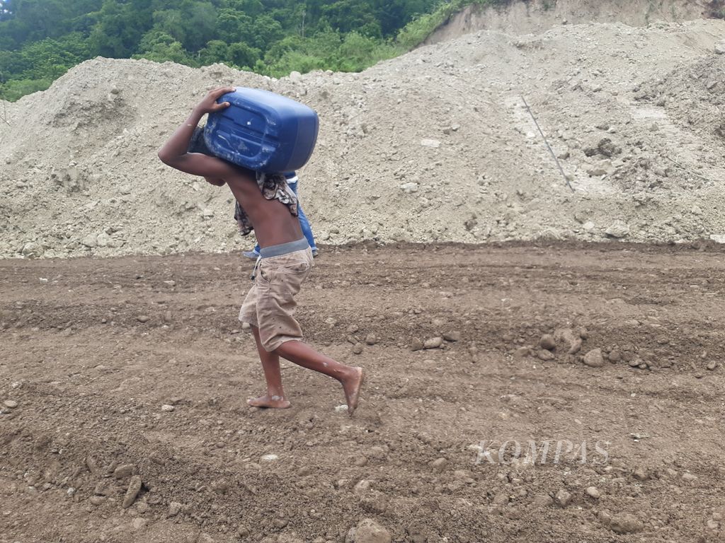 Seorang remaja memikul jeriken berisi bahan bakar melewati lokasi longsor Kelurahan Takari, Kabupaten Kupang, Nusa Tenggara Timur, pada Senin (20/2/2023). Longsor menghambat mobilitas logistik, termasuk bahan bakar.