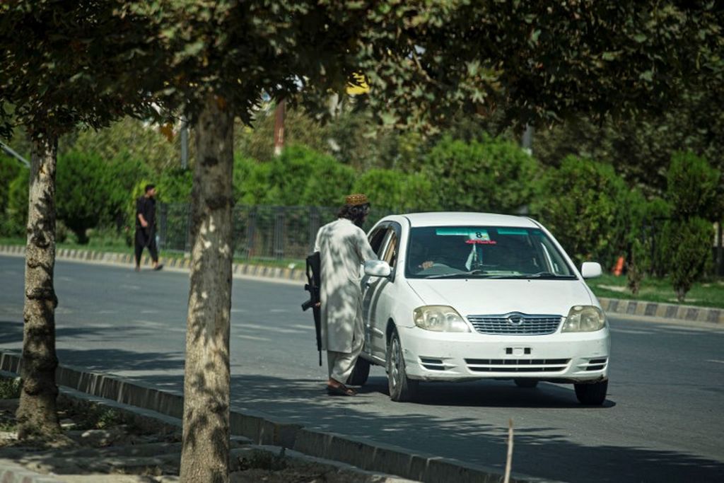 Seorang anggota Taliban berbicara dengan maksud merazia pengendara di dekat Kedutaan Besar Rusia setelah serangan bunuh diri di Kabul pada 5 September 2022. 