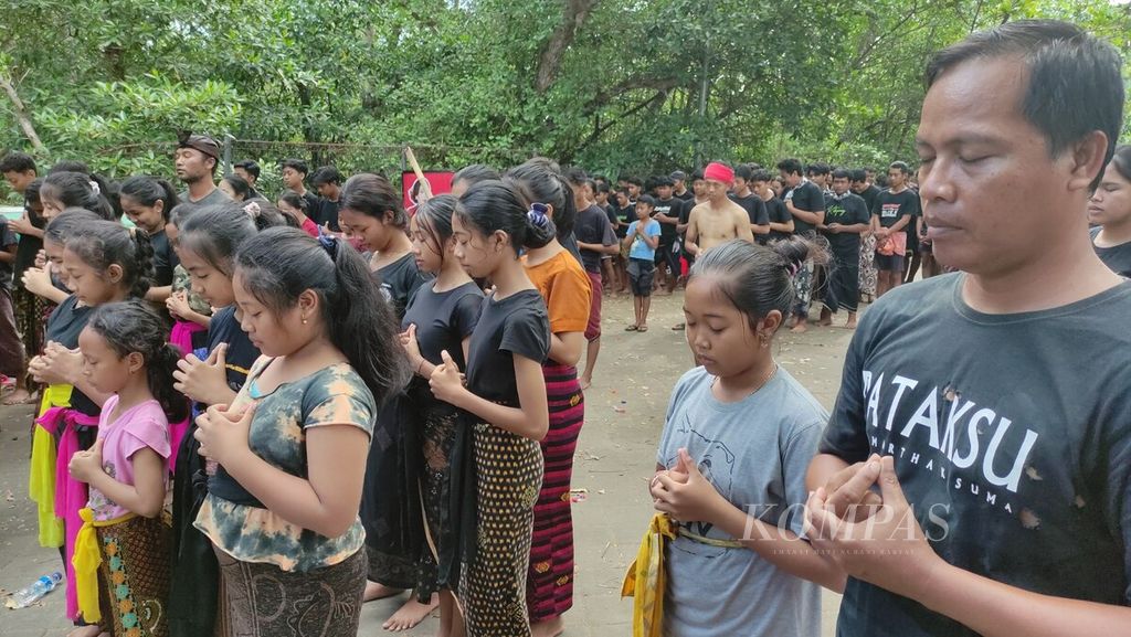 <i>Krama </i>(warga) dan <i>yowana </i>(pemuda dan pemudi) Desa Adat Kedonganan, Kedonganan, Kuta, Kabupaten Badung, berdoa bersama di pelataran Pura Dalem Kahyangan Desa Adat Kedonganan sebelum mengikuti tradisi <i>mabuug-buugan </i>di tengah hutan mangrove Taman Hutan Raya Ngurah Rai, Kamis (23/3/2023).