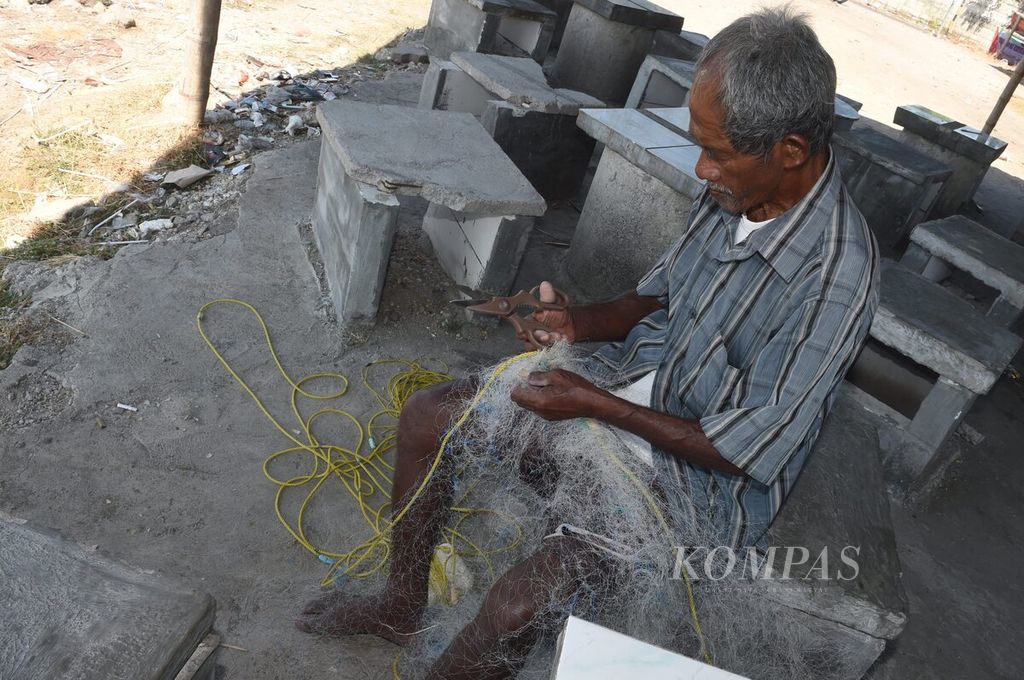 Asmali memperbaiki jaringnya yang rusak di Pantai Tambak Wedi, Kota Surabaya, Jawa Timur, Senin (29/8/2022). Sebagian besar nelayan setempat membeli pertalite sebagai bahan bakar mesin perahunya secara eceran. Untuk 1 liter pertalite, mereka beli seharga Rp 10.000. Dalam sehari, nelayan menghabiskan 3-5 liter pertalite.