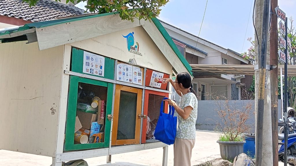 Risna Rita Arlianti (41), warga perumahan DGading Hill, Rangga Mekar, Bogor Selatan, Kota Bogor, Jawa Barat, saat memasukkan sampah yang telah ia pilah dari rumahnya ke dalam pos pandai, Kamis (31/8/2023). Pos pandai ini merupakan hasil swadaya warga untuk mengatasi permasalahan sampah rumah tangga.