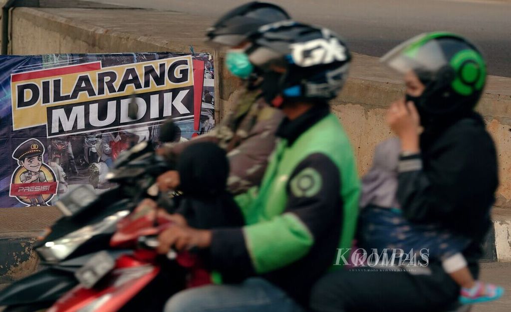 Warga melintasi baliho larangan mudik di perbatasan Jakarta dan Bekasi di Pondok Kelapa, Jakarta Timur, Kamis (22/4/2021). 