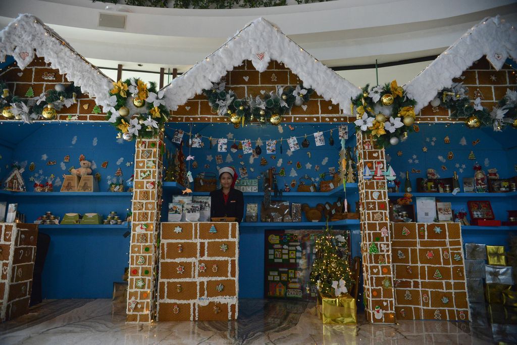 Petugas hotel berdiri di dalam rumah kue jahe raksasa di lobi Hotel Gran Melia, Setiabudi, Jakarta Selatan, Rabu (21/12/2022). Berbagai pernak-pernik Natal menghiasi sejumlah sudut Hotel Gran Melia.
