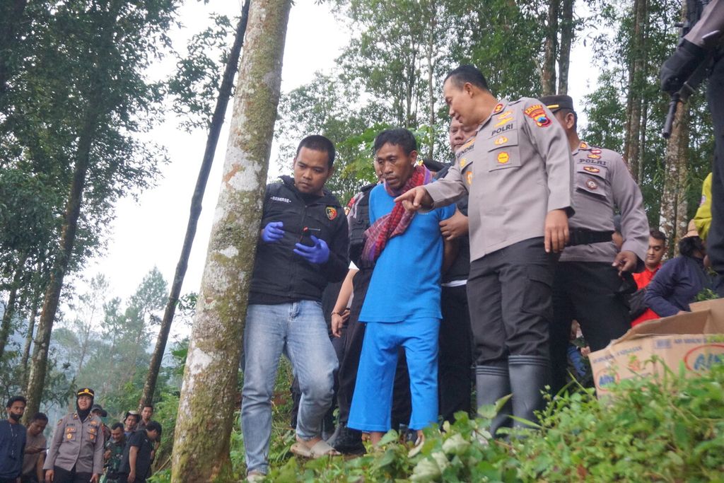 Slamet Tohari (center) was brought by the Banjarnegara Police to the cassava garden where the 12 victims he killed were buried in Balun Village, Wanayasa, Banjarnegara, Central Java, Tuesday (4/4/2023).