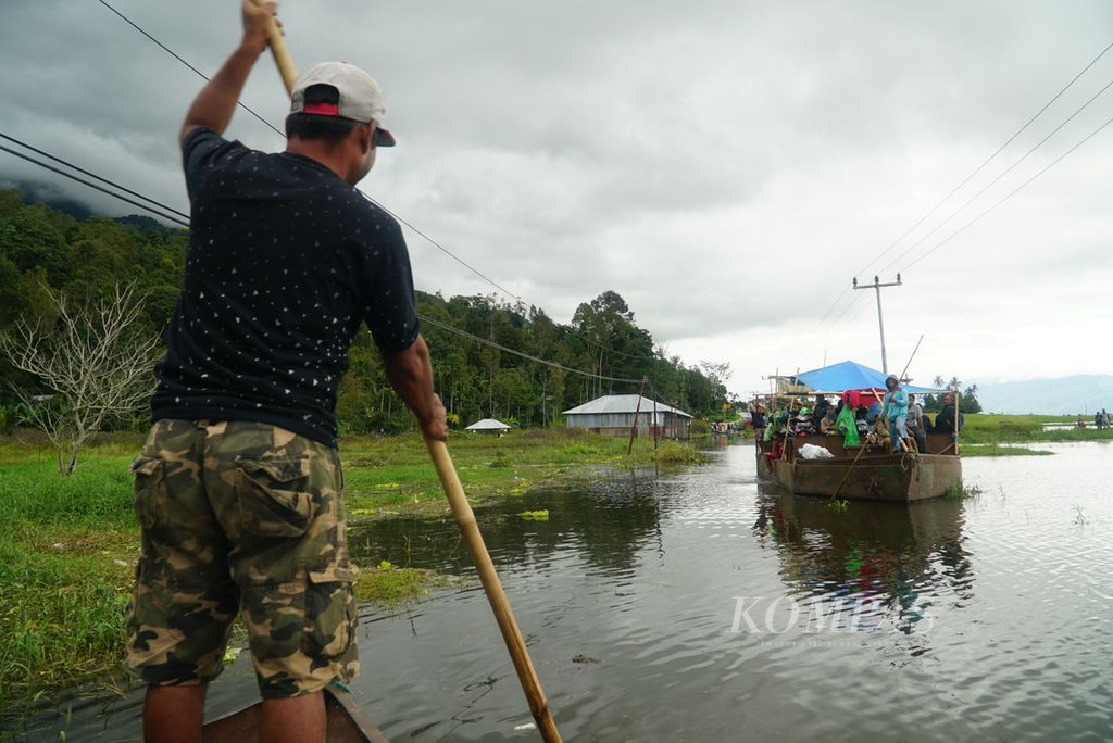 Warga mendayung perahu petambang pasir untuk mengantar penumpang melintasi jalan provinsi yang terendam banjir akibat meluapnya Danau Kerinci di Desa Semerap, Kecamatan Keliling Danau, Kabupaten Kerinci, Jambi, Selasa (16/1/2024). 