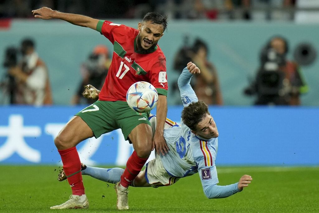 Pemain Spanyol, Gavi (kanan), berduel dalam perebutan bola dengan pemain Maroko, Sofiane Boufal, pada pertandingan babak 16 besar Piala Dunia Qatar di Stadion Education City di Al Rayyan, Qatar, Selasa (6/12/2022). Meski mendominasi penguasaan bola Spanyol gagal mencetak gol di babak pertama yang berakhir dengan skor 0-0. Spanyol lantas kalah lewat adu penalti.