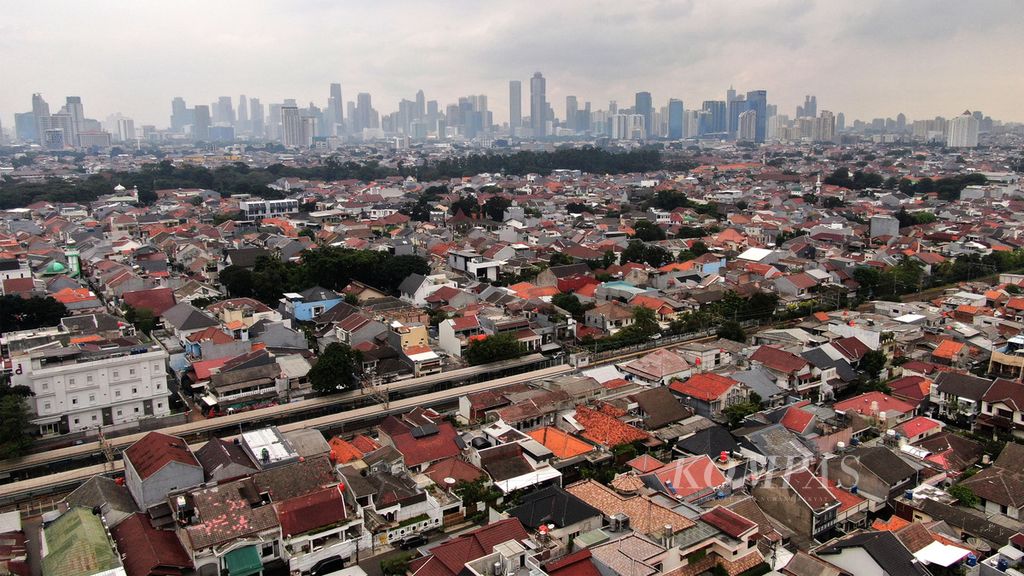 Kawasan permukiman padat penduduk dengan latar belakang gedung bertingkat di Jakarta, Rabu (18/1/2023). 